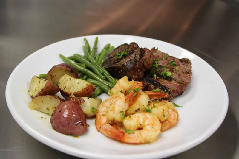 Chef-prepared steak, shrimp, potatoes and vegetables plated for a Riviera event